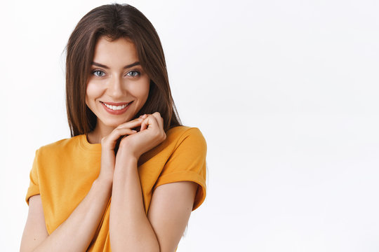 Close-up feminine flirty and romantic young girlfriend in yellow t-shirt, making silly tender expression, clasp hands near face and giggle coquettish as asking partner favor, white background