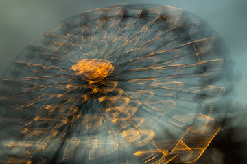 Blurred ferris wheel in motion at the amusement park, night illumination. Long exposure.