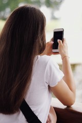 Fototapeta na wymiar Young pretty girl's using smartphone with city on background