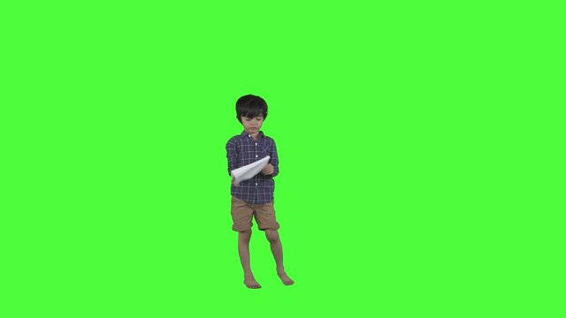 Happy little boy playing a paper plane in the studio. Shot in 4k resolution with green screen background