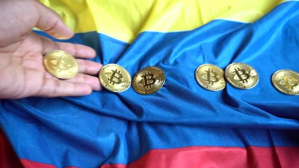 hand of black man spreading bitcoins over Colombian flag - Powered by Adobe