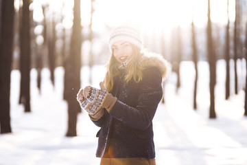 Portrait of young beautiful girl with long hair, in a blue jacket and knitted hat and mittens...