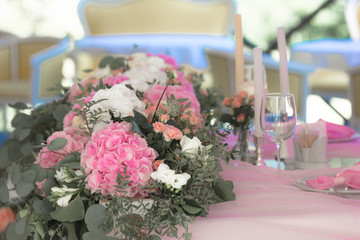 Candle, White flowers in modern glass vase on pink centerpiece. Stylish luxury decor on wedding table.Luxury catering and adorning. Holiday feast