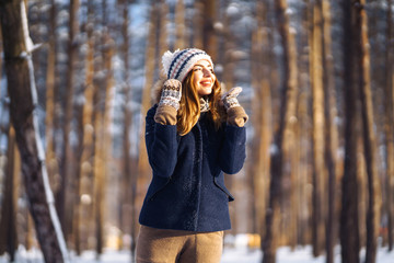 Portrait of young beautiful girl with long hair, in a blue jacket and knitted hat and mittens...