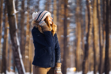 Portrait of young beautiful girl with long hair, in a blue jacket and knitted hat and mittens...