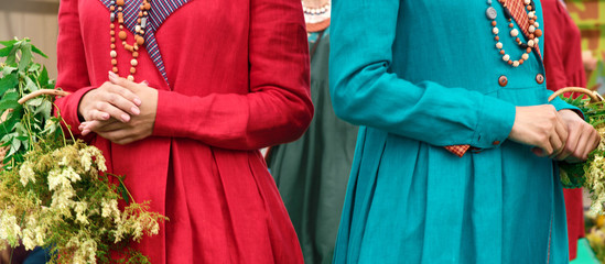 Fototapeta na wymiar two girls in linen dresses with baskets of grass