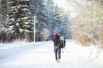 A man travels with a backpack. Winter hike in the forest. Tourist on a walk in the winter in the park.