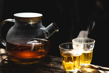 The steam from a cup or pot of coffee or tea on the old wood table and black background, Warm drinks make good healthy, Selective focus.