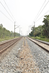 railway track with the background of sky, and green trees on both sides of the track.