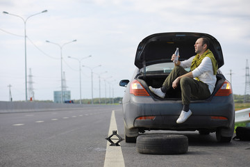 Replacing the wheel of a car on the road. A man doing tire work on the sidelines.