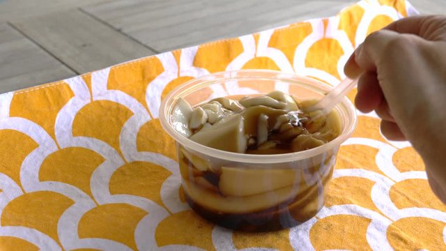 Soybean pudding (Taufufa) with brown sugar syrup in a plastic container. Delicious sweet dessert.