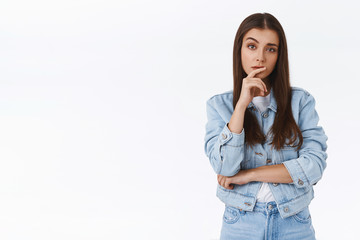 Skeptical, suspicious serious-looking thoughtful caucasian girl in denim jacket, touching lip and...