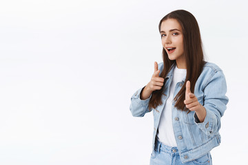 Sassy stylish and cool attractive brunette woman in denim jacket, pointing finger pistols camera...