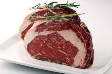 Raw fresh meat Ribeye Steak, seasoning and meat fork on rustic background