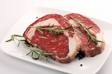 Raw fresh meat Ribeye Steak, seasoning and meat fork on rustic background