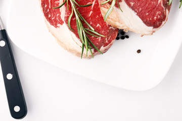 Raw fresh meat Ribeye Steak, seasoning and meat fork on rustic background