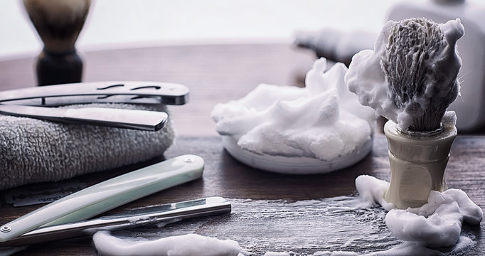 Shaving accessories on a wooden texture background. Tools. Disposable shaving machine, brush, foam and hazard razor.