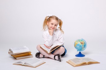 little girl in school uniform  on a white background reading a book