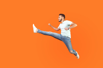 Full body portrait of excited brunette man with beard in sneakers and denim outfit jumping over in...