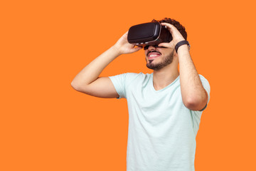 Portrait of happy gamer, brunette man with beard in t-shirt wearing vr headset, playing virtual...