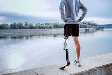Rear view of fit healthy Caucasian handicapped man in sportswear and with artificial leg standing...