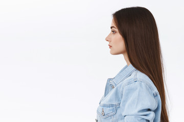 Profile portrait serious-looking, determined and confident attractive modern 20s woman in denim jacket, standing in elevator or subway, waiting in queue with calm unbothered, casual expression