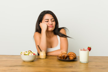 Young curvy woman taking a breakfast who feels sad and pensive, looking at copy space.