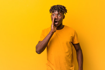 Fototapeta premium Young black man wearing rastas over yellow background is saying a secret hot braking news and looking aside