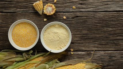 Polenta corn grits and corn flour in a porcelain bowl on a wooden table. Ears of corn and pieces of corn next to bowls. Gluten Free Healthy Eating