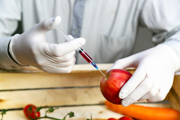 Chemical processing of fruits, fertilizers and pesticides A man injects chemicals into an orange,...