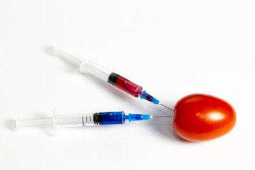 Two syringes with chemicals near a branch of tomatoes. Syringes with chemicals for fertilizing...