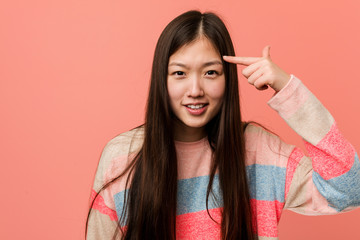 Young cool chinese woman showing a disappointment gesture with forefinger.
