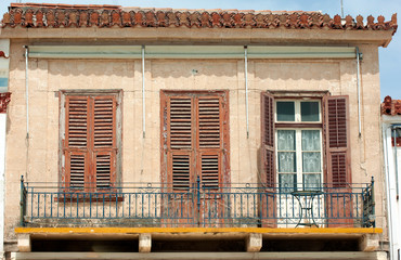 Fototapeta na wymiar The facade of a neoclassical building at the port of the Greek island of Aegina. Dilapidated and weathered it may be, but the elegance of the architectural design, shines through.