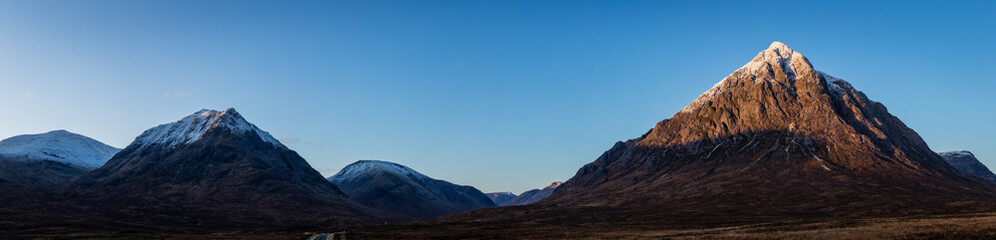 buachaille etive mor and the surrounding mountains of glencoe and rannoch moor in the argyll region of the highlands of scotland during a crisp clear blue winter sunrise