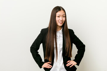 Young pretty chinese business woman confident keeping hands on hips.