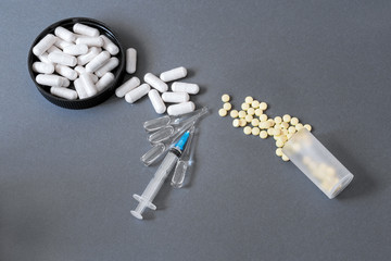 Fototapeta na wymiar Pills, capsules and a medical syringe with ampoules on a dark background. Healthcare and pharmacology concept. Top view, free space.