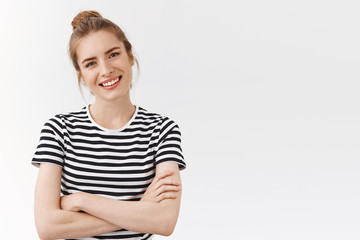 Waist-up shot lucky, confident good-looking woman with messy bun in striped t-shirt, cross hands chest, tilt head and smiling looking like professional, being self-assured and encouraged