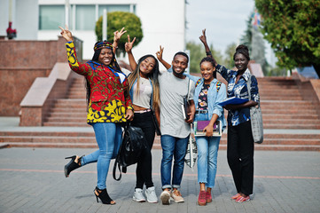 Group of five african college students spending time together on campus at university yard. Black...