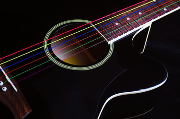Fototapeta na wymiar Black acoustic guitar with multi-colored strings. Close-up.