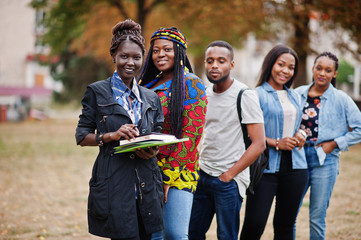 Row of group five african college students spending time together on campus at university yard....