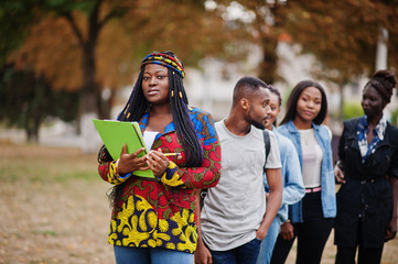 Row of group five african college students spending time together on campus at university yard....