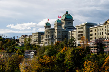 The Swiss Parliament Building (1902) with river Aare called Bundeshaus in Berne with waving swiss...