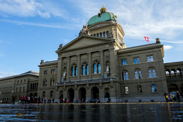 Fototapeta premium The Swiss Parliament Building (1902) with river Aare called Bundeshaus in Berne with waving swiss flags.