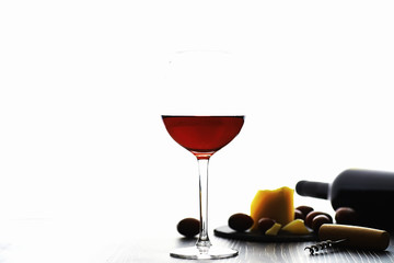 A glass of red dry wine on the table. Dark bottle and glass of wine.