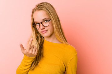 Adorable teenager woman pointing with finger at you as if inviting come closer.