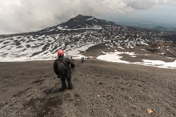 People walking on Mount Etna, active volcano on the east coast of Sicily, Italy. Panorama of Mount Etna the highest volcano in Europe.