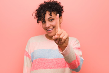 Young mixed african american teenager woman showing number one with finger.