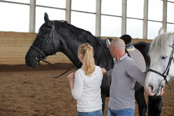 People on a horse training in a wooden arena
