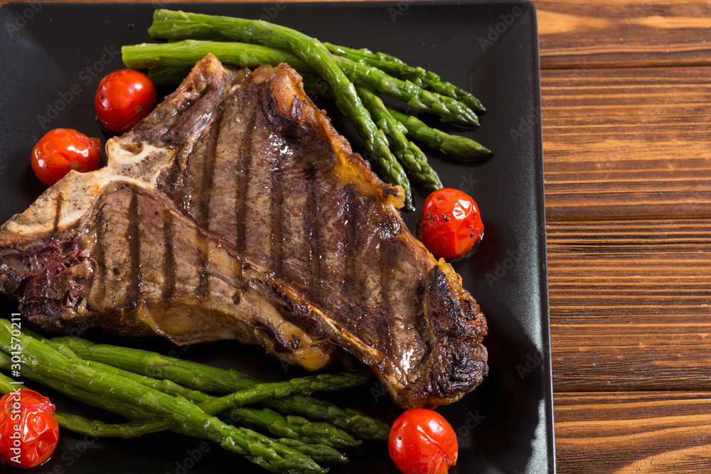 Wall mural Grilled T-bone steak with asparagus and cherry tomatoes