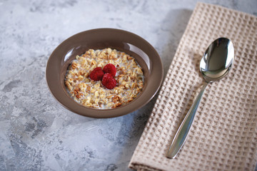 Baked granola with milk and raspberries in a plate. Healthy breakfast. Tasty muesli, snack.